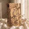Cover of a camel and gold embroidered Nikkah booklet with a crystal crescent moon and gold initial