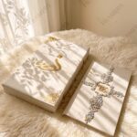 Ivory crystal Nikkah booklet with initials beside a matching ivory box with gold calligraphy
