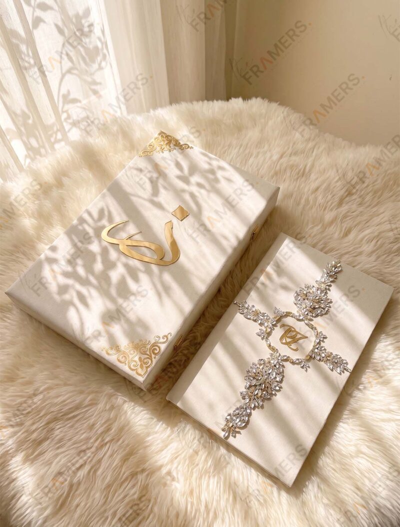 Ivory crystal Nikkah booklet next to a matching ivory keepsake box with a gold calligraphy letter